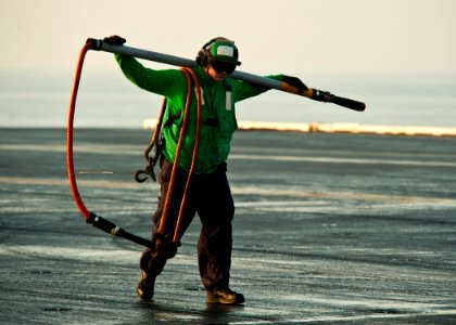 US Navy 120105-N-BT887-025 Logistics Specialist Seaman Tyler Thibault carries a hook across the flight deck during vertical replenishment aboard th