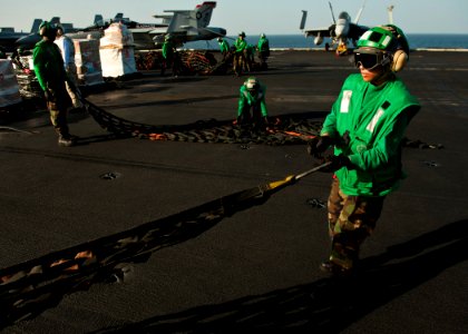 US Navy 120105-N-BT887-383 Logistics Specialist Seaman Tomiya Norris bundles a cargo net during a vertical replenishment aboard the Nimitz-class ai