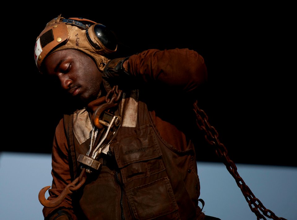 US Navy 120110-N-DR144-180 Aviation Electrician's Mate Airman Michael Johnson carries tie-down chains to an F-A-18E Super Hornet aboard the Nimitz