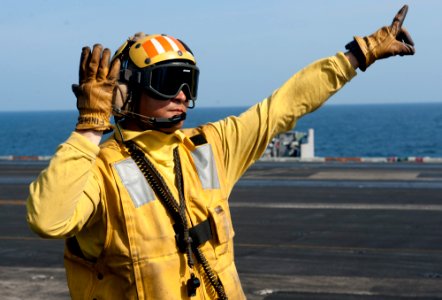 US Navy 120105-N-OY799-521 Aviation Boatswain's Mate 2nd Class Forrest Findley directs a fixed-wing aircraft on the flight deck of the Nimitz-class