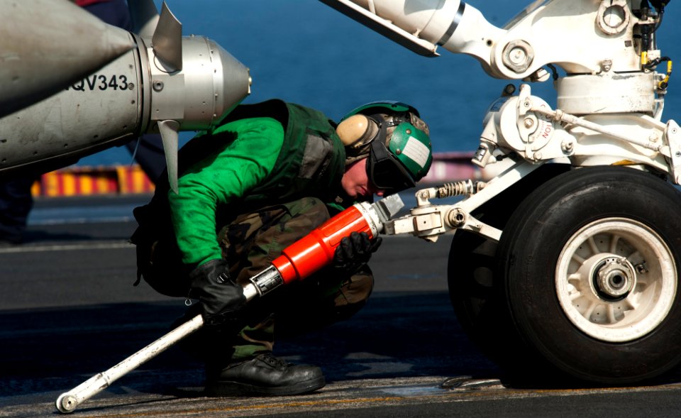 US Navy 120110-N-OY799-275 Aviation Boatswain's Mate (Equipment) Airman Apprentice Jonathan Benoit attaches a hold back bar to an F-A-18F Super Hor
