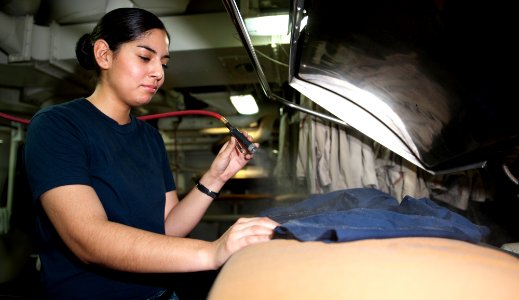 US Navy 120112-N-OY799-065 Aviation Boatswain's Mate (Handling) Airman Michelle Eilders sprays water on a smock in ship's laundry aboard the Nimitz