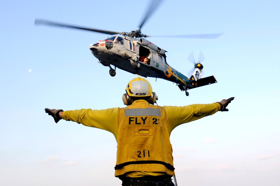 US Navy 120113-N-RG587-395 Aviation Boatswain's Mate (Handling) 2nd Class Juan Arciniega signals an MH-60S Sea Hawk helicopter assigned to Helicopt