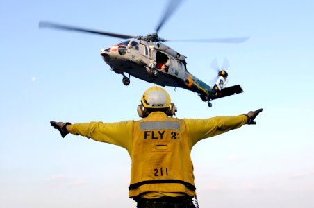 US Navy 120113-N-RG587-395 Aviation Boatswain's Mate (Handling) 2nd Class Juan Arciniega signals an MH-60S Sea Hawk helicopter assigned to Helicopt