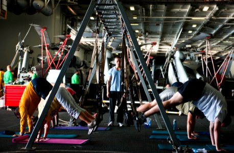 US Navy 120112-N-GC412-037 Sailors participate in a total resistance training (TRX) class in the hangar bay aboard the Nimitz-class aircraft carrie