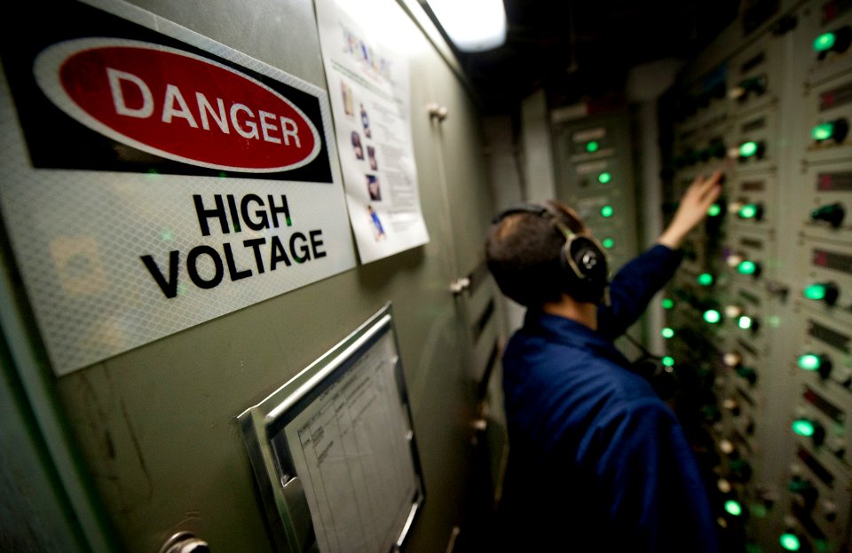 US Navy 120110-N-DR144-521 Electrician's Mate 3rd Class Michael Seed restores power from an electrical load center after a loss of power drill