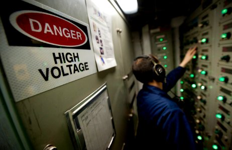 US Navy 120110-N-DR144-521 Electrician's Mate 3rd Class Michael Seed restores power from an electrical load center after a loss of power drill