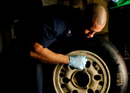US Navy 120112-N-ZI635-095 Aviation Structural Mechanic 2nd Class Christian Samaras, performs maintenance on the tire of an F-A-18C Hornet aboard t