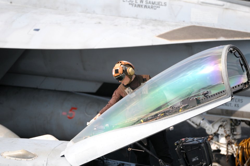 US Navy 120111-N-GZ832-336 A plane captain cleans the canopy of an F-A 18C Hornet on the flight deck aboard the Nimitz-class aircraft carrier USS C
