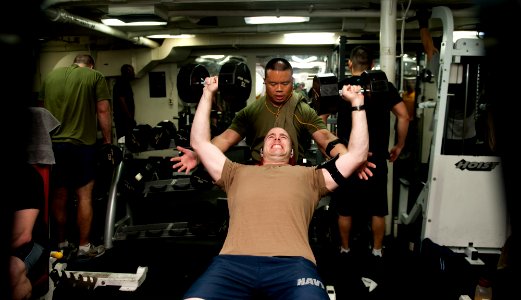 US Navy 120108-N-OY799-246 Lt. Cmdr. Kevin Gue, from Oakland, Calif., spots Lt. Todd Leroux, from San Diego, during a session of weightlifting aboa