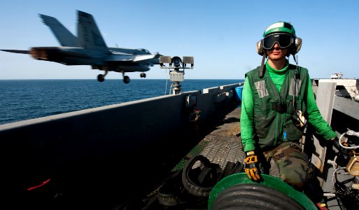 US Navy 120117-N-OY799-092 Aviation Boatswain's Mate (Equipment) Airman Krzysztof Urbanik observes an F-A-18C Hornet land
