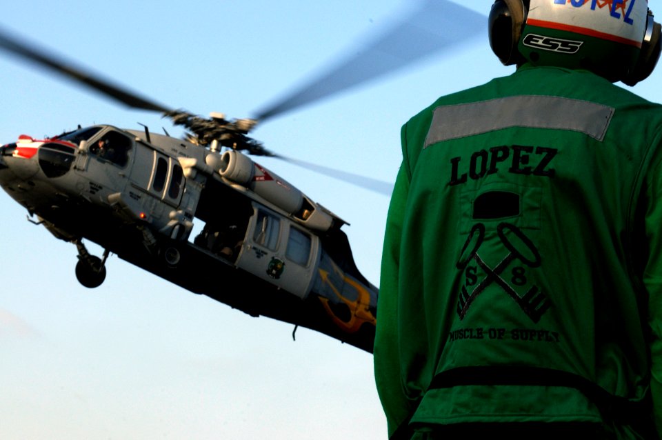 US Navy 120113-N-RG587-329 Logistics Specialist 3rd Class Roberto Lopez watches as an MH-60S Sea Hawk helicopter assigned to Helicopter Sea Combat