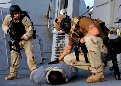 US Navy 120114-N-VH839-086 Senior Chief Damage Controlman Jared Klink and a U.S. Coast Guardsman apprehend a suspected pirate aboard the Arleigh Bu