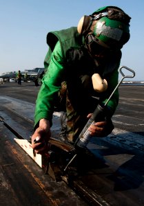 US Navy 120111-N-OY799-065 Aviation Boatswain's Mate (Equipment) Airman Krzysztof Urbanik greases the catapult shuttle on the flight deck of the Ni