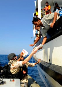 US Navy 120118-N-ZZ999-002 Sailors from the guided-missile destroyer USS Dewey's (DDG 105) visit, board, search and seizure team provide food, wate photo