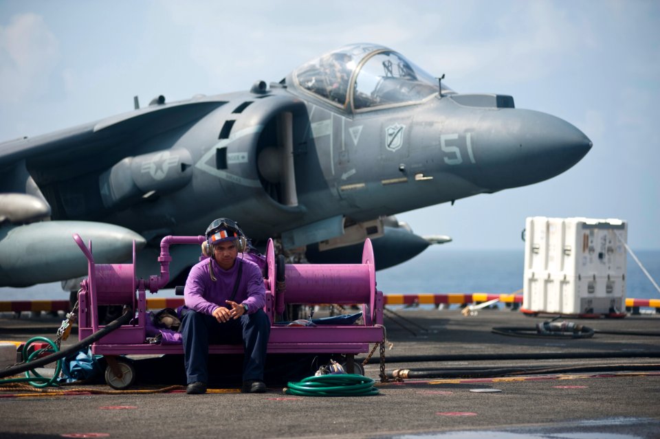 US Navy 120114-N-DX615-282 Aviation Boatswains Mate (Fuels) 2nd Class Ron Ramos waits near an AV-8B Harrier before defueling the aircraft aboard th