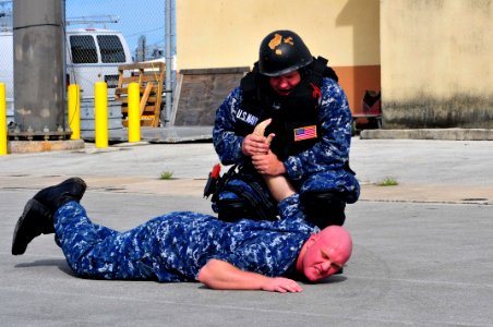 US Navy 120118-N-JH293-025 Machinist's Mate 2nd Class Robert Gaylor, assigned to the submarine tender USS Emory S. Land (AS 39), apprehends Gunner' photo