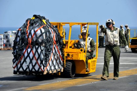 US Navy 120116-N-KD852-039 Marines from Combat Cargo assigned to 11th Marine Expeditionary Unit (11th MEU) move supplies across the flight deck abo