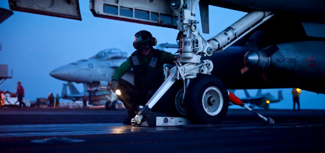 US Navy 120115-N-OY799-351 Aviation Boatswain's Mate (Equipment) 3rd Class Adam Fitzgerald checks the shuttle for the launching of an F-A-18C Hornet