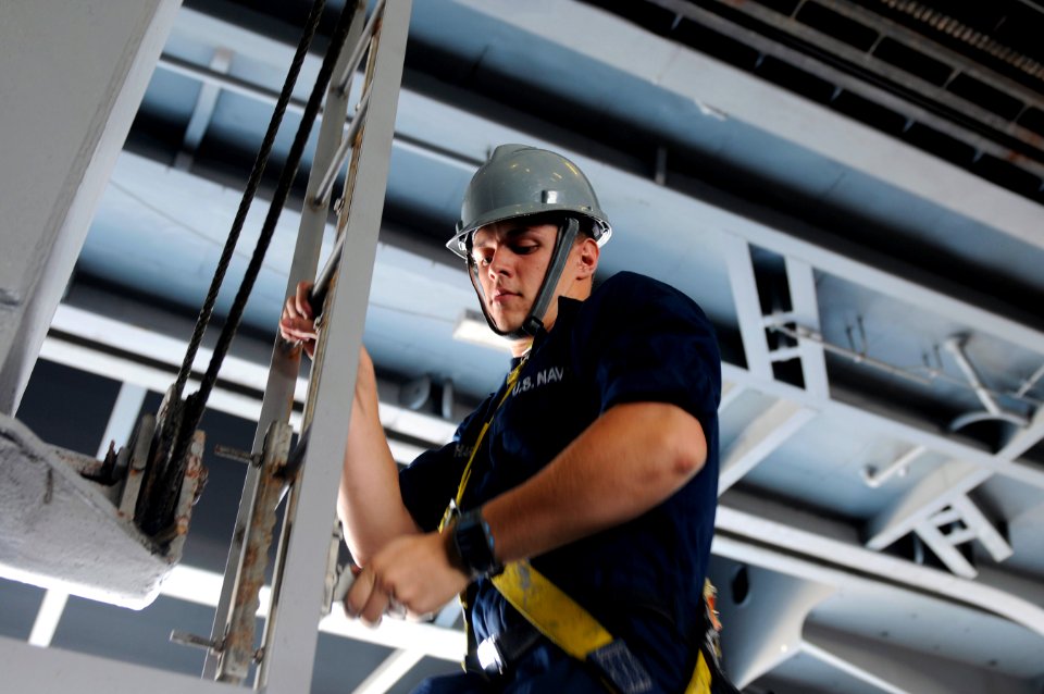 US Navy 120118-N-RG587-268 Seaman Apprentice Jordan Cocchiarella descends the ladder of a sliding padeye after performing maintenance in the hangar