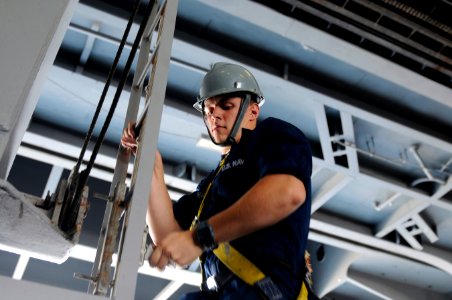 US Navy 120118-N-RG587-268 Seaman Apprentice Jordan Cocchiarella descends the ladder of a sliding padeye after performing maintenance in the hangar