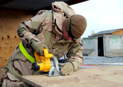 US Navy 120122-N-SD610-002 Builder Constructionman Reginal Skinner, assigned to Naval Mobile Construction Battalion (NMCB) 7, operates a skill saw photo