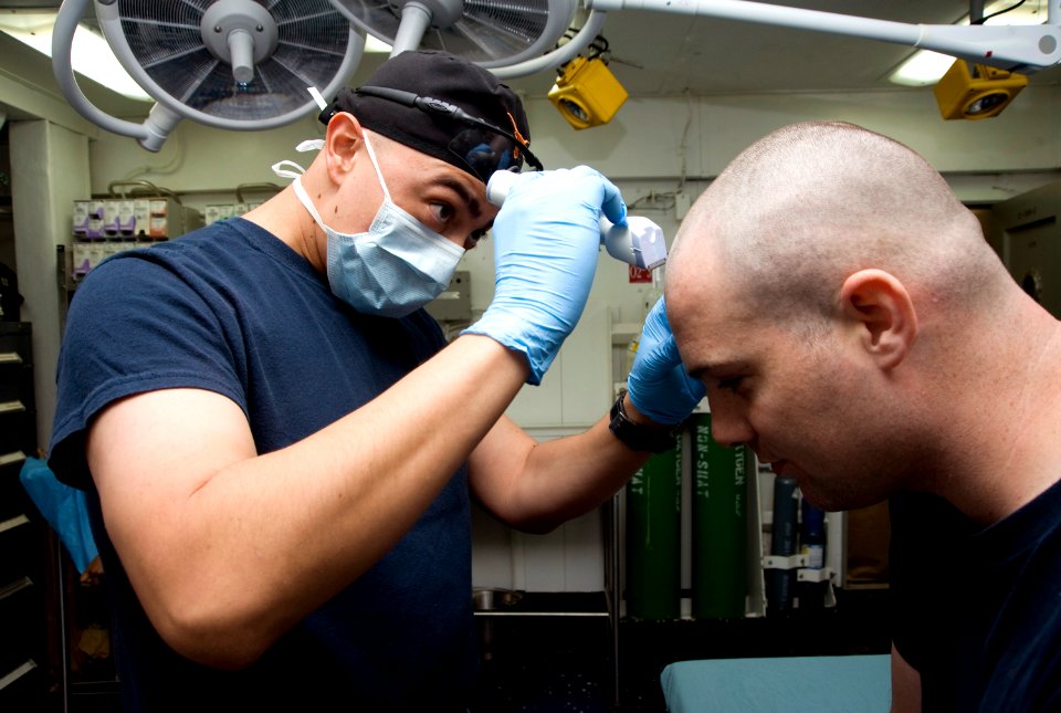 US Navy 120120-N-JN664-010 Hospital Corpsman 1st Class Albert Aguilar shaves the head of Mass Communication Specialist 2nd Class Christopher Dollar