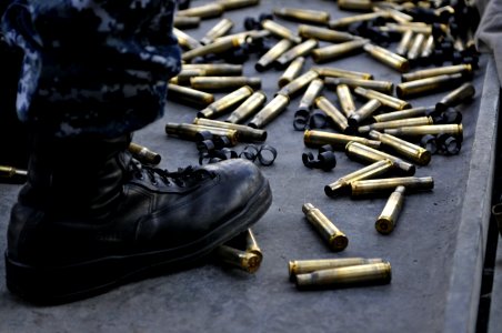 US Navy 120118-N-ZI635-361 Shell casings from a .50 caliber machine gun collect around the feet of Aviation Ordnanceman 3rd Class Jeffery Harris as