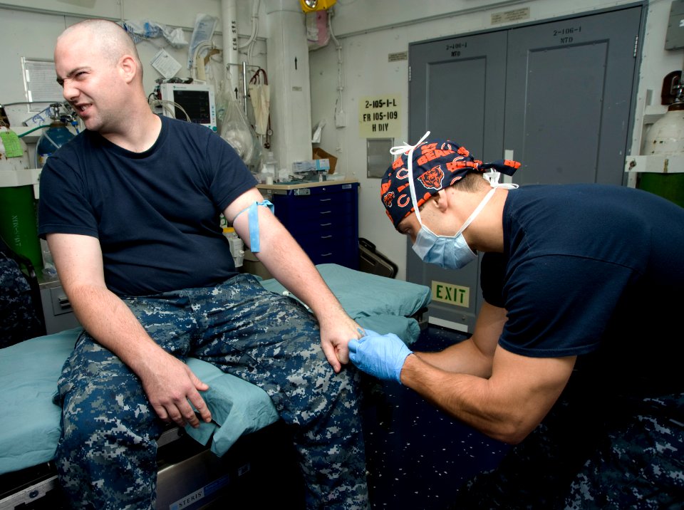US Navy 120120-N-JN664-018 Hospital Corpsman 1st Class Albert Aguilar inserts an intravenous tube into the arm of Mass Communication Specialist 2nd