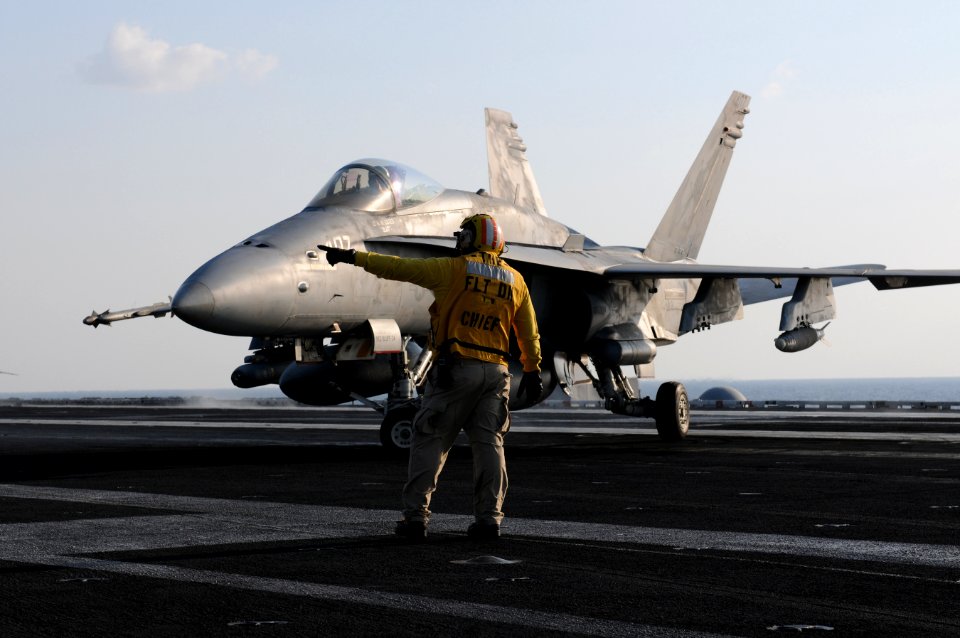 US Navy 120125-N-GZ832-238 Chief Aviation Boatswain's Mate Scott Cook directs an F-A 18C Hornet