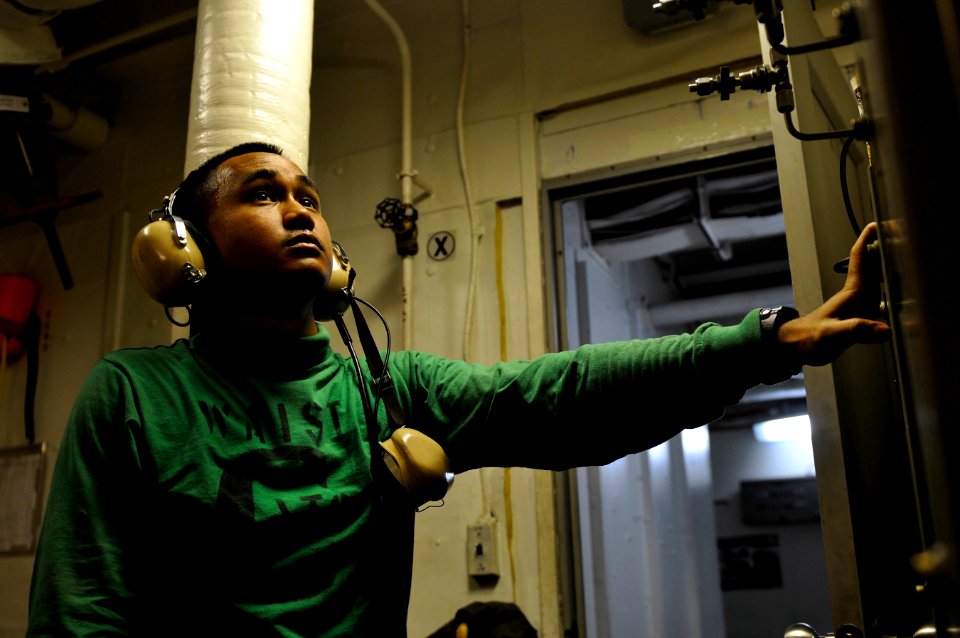US Navy 120121-N-UT411-016 Aviation Boatswain's Mate (Equipment) 3rd Class John Johnson monitors controls for a catapult water brake aboard the Nim