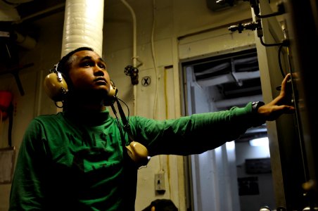 US Navy 120121-N-UT411-016 Aviation Boatswain's Mate (Equipment) 3rd Class John Johnson monitors controls for a catapult water brake aboard the Nim