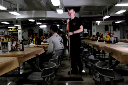 US Navy 120124-N-RG587-172 Aviation Electrician's Mate Airman Grant Godfrey sweeps the mess decks aboard the Nimitz-class aircraft carrier USS Carl