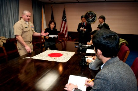 US Navy 120125-N-AG621-025 Lt. j.g. Michael Reid unveils a World War II-era Japanese flag to reporters from the Yokosuka Press Club