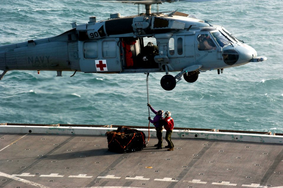 US Navy 120121-N-PB383-212 Sailors attach a cargo holder to an MH-60S Sea Hawk helicopter assigned to Helicopter Sea Combat Squadron (HSC) 21 on th