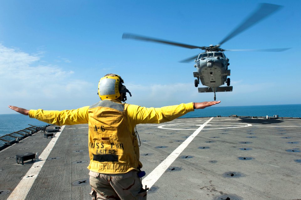 US Navy 120126-N-KS651-086 Boatswain's Mate 3rd Class Allison Mulligan signals an MH-60S Sea Hawk helicopter to land on the flight deck of the amph