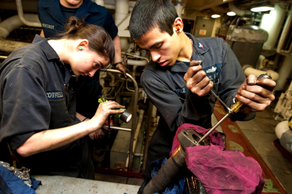 US Navy 120124-N-PB383-857 Engineman Fireman Recruit Megan Cotrell and Engineman 2nd Class Richard Cruz conduct maintenance on an engine part in on