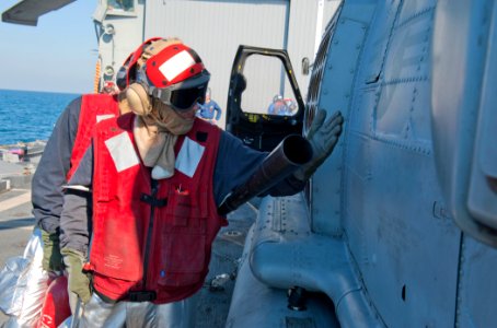 US Navy 120124-N-VY256-030 Damage Controlman Fireman Apprentice Ryan Collier tests for heat on an MH-60R Sea Hawk helicopter