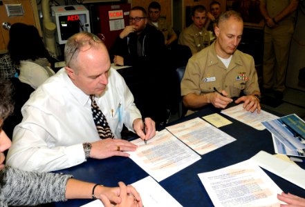 US Navy 120125-N-GU530-067 James Sketchley and Cmdr. Jeffrey Farah sign documents recognizing the adoption of the Henry M. Jackson by the Everett a