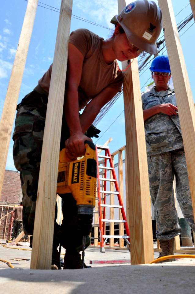 US Navy 120127-A-TF780-202 Steelworker 2nd Class Rejuny Caswell drills anchor holes into a pre-fabricated wall frame for a wall at Escuela Commodor