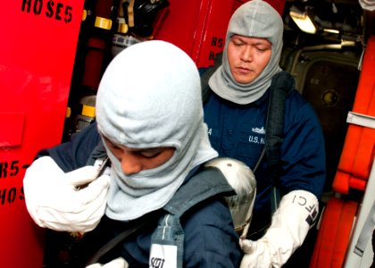 US Navy 120127-N-OH194-008 Fire Controlman 1st Class Eric Gabriel Gonzaga helps Damage Controlman 3rd Class Cris Niosco don a self-contained breath