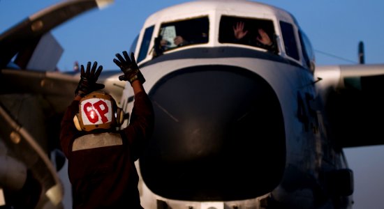 US Navy 120126-N-TZ605-182 A Sailor signals to the pilots of a C-2A Greyhound assigned to Fleet Logistics Support Squadron (VRC) 40 during startup