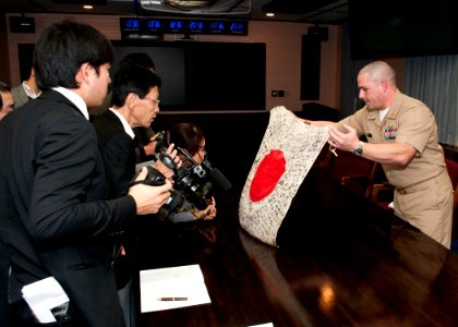 US Navy 120125-N-AG621-015 Lt. j.g. Michael Reid unveils a World War II-era Japanese flag to reporters from the Yokosuka Press Club