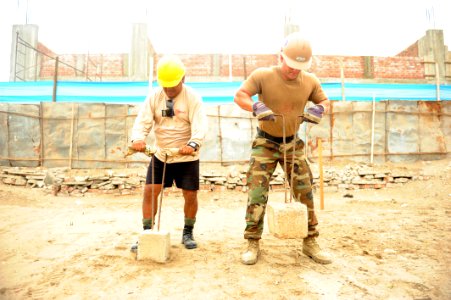 US Navy 120125-N-MN502-026 Equipment Operator Justin Holden works with a Peruvian marine to tamp down an area