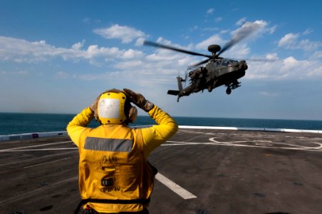 US Navy 120127-N-PB383-629 Aviation Boatswain's Mate (Handling) 2nd Class Tanner Kent guides a U.S. Army AH-64 Apache helicopter to the flight deck