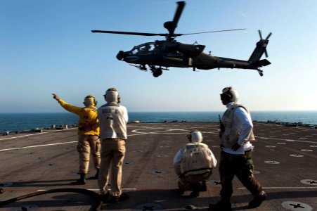 US Navy 120128-N-KS651-063 Boatswain's Mate 3rd Class Allison Mulligan signals an AH-64 Apache helicopter to depart the flight deck of amphibious d