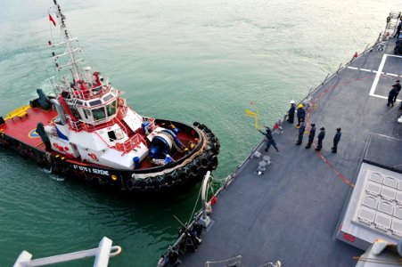 US Navy 120130-N-ED900-166 A Sailor throws a line to a tugboat