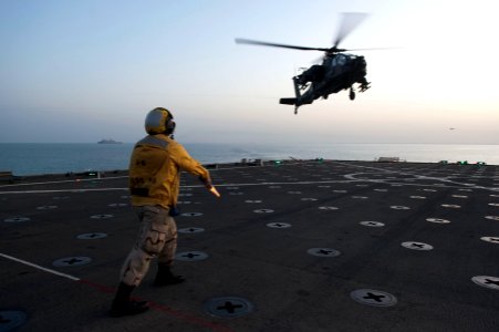 US Navy 120130-N-KS651-267 Boatswain's Mate 3rd Class Victoria Contreras signals a U.S. Army AH-64 Apache helicopter to land on the flight deck of
