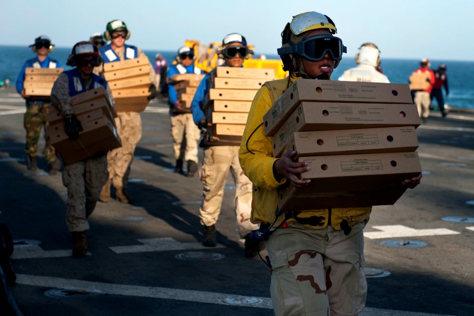US Navy 120129-N-KS651-181 Sailors aboard the amphibious dock landing ship USS Pearl Harbor (LSD 52) carry supplies from the flight deck during a r