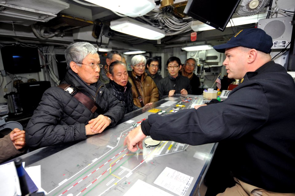 US Navy 120202-N-KM939-008 Lt. Cmdr. Dave Hecht conducts a tour of Flight Deck Control with Japanese visitors aboard the nuclear-powered aircraft c